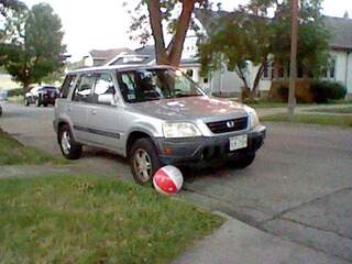 plastic beach ball against the tire of Lucia's car.